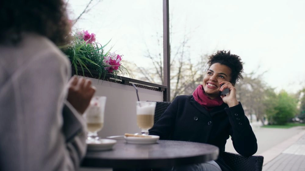 Duas mulheres conversando enquanto tomando um capuccino em uma cafeteria